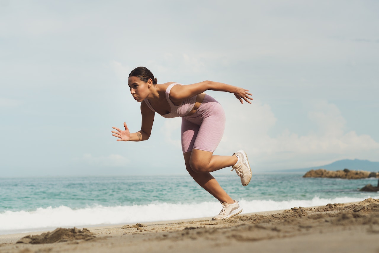Woman running at the sand in running shoes Nike