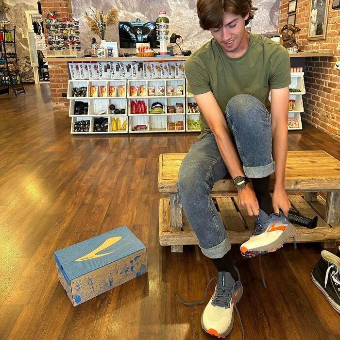 A man is putting on Brooks Cascadia 17 running shoes